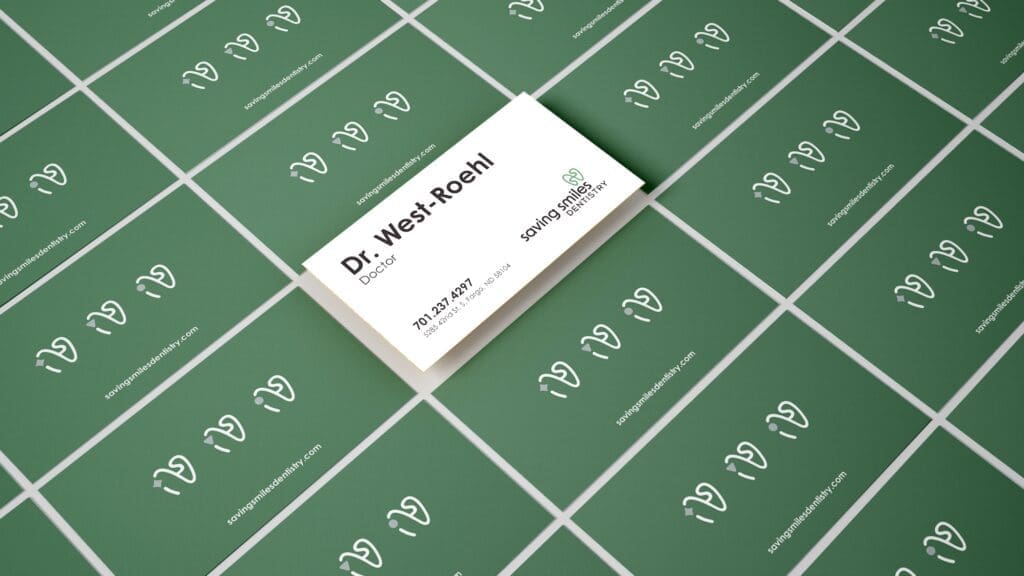 Mockup of business cards for Saving Smiles, showing the front design on a green background.